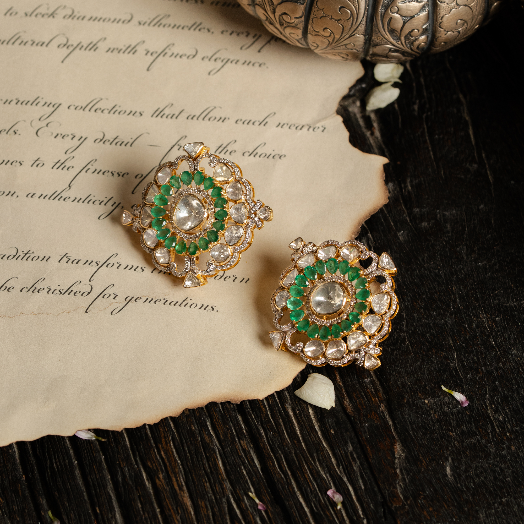 An oversized, ornate polki diamond stud earring featuring a central polki diamond surrounded by a halo of vibrant emeralds and an outer frame of larger uncut diamond stones in india