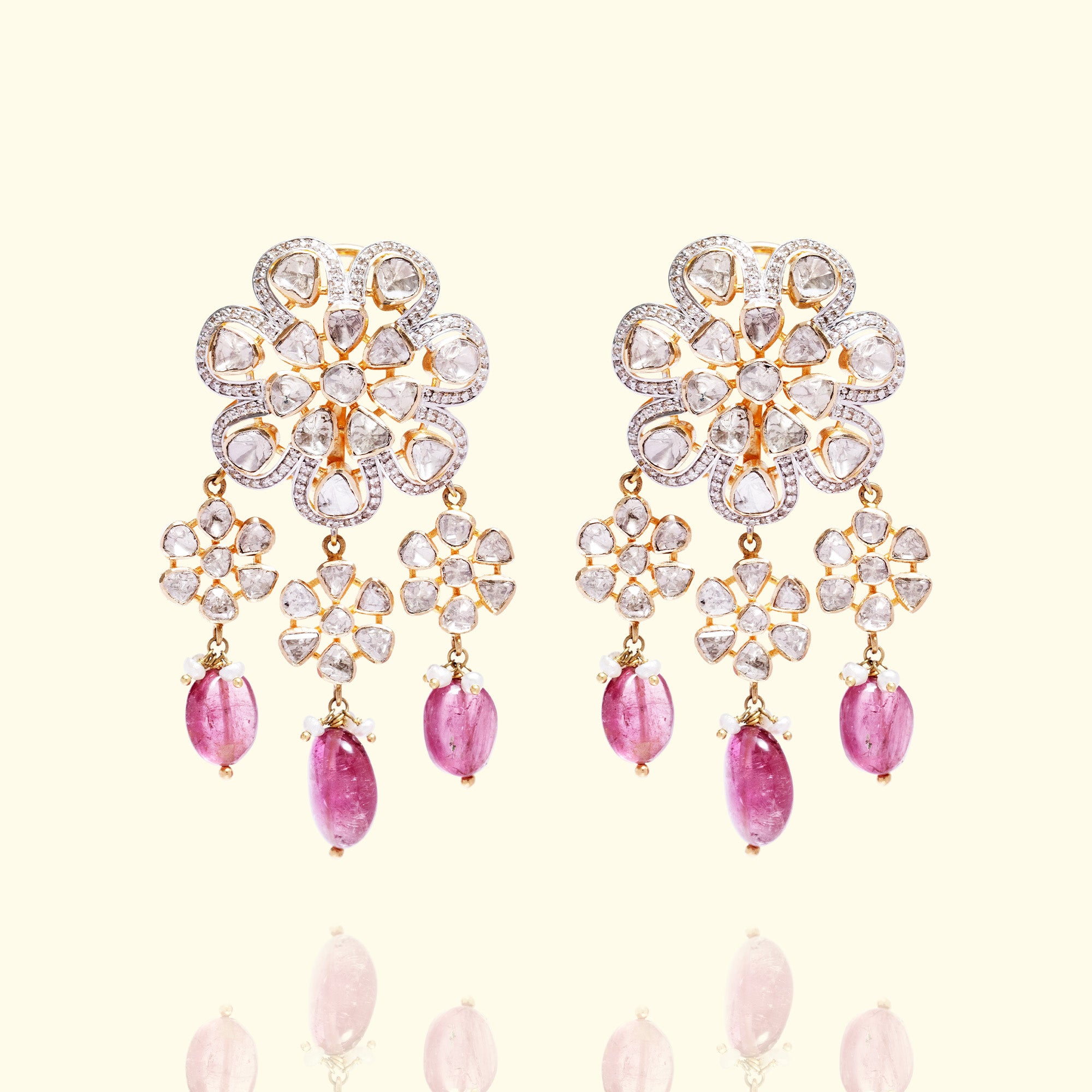 Pair of gold floral Polki chandelier earrings featuring polki diamond-set flower studs and dangling pink tourmaline droplets with seed pearl accents.