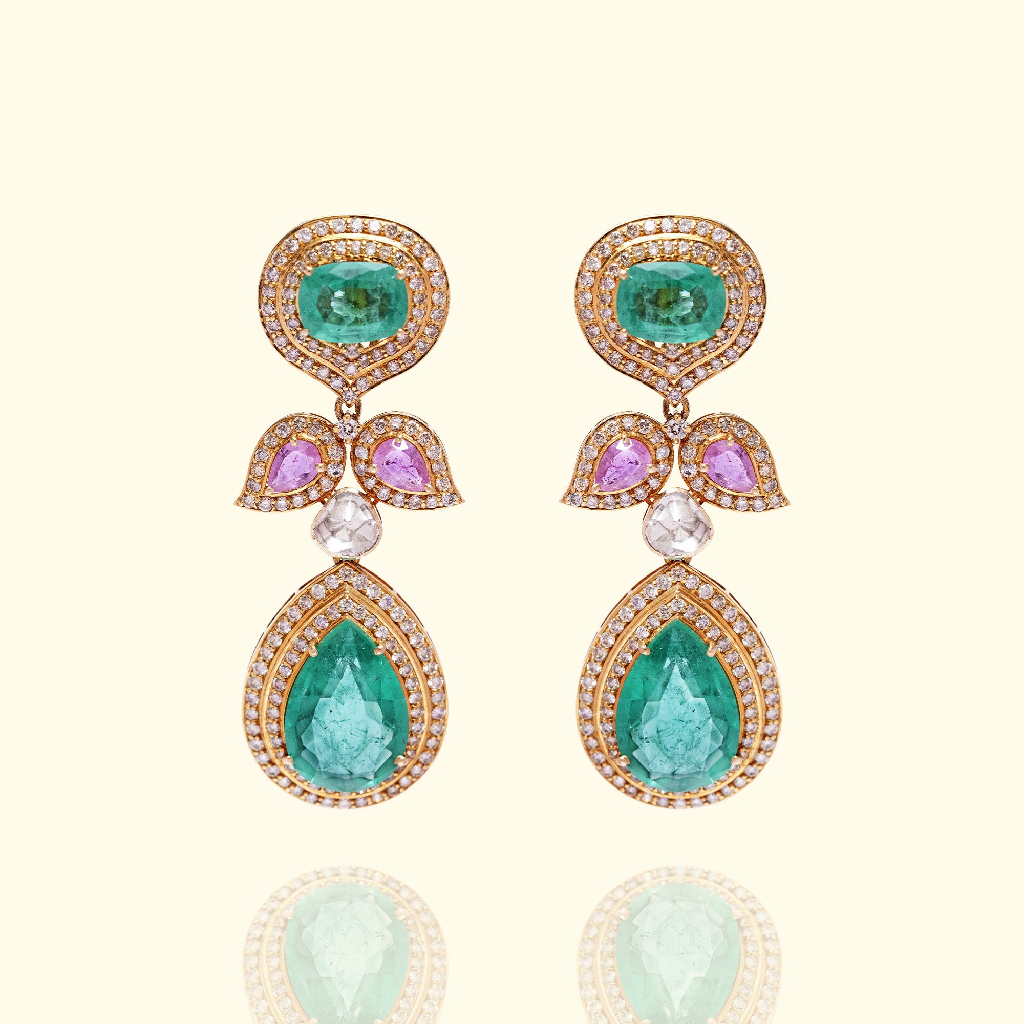 A regal triple-tier drop earrings featuring a round emerald stud, a leaf-motif center with pink sapphires, and a large pear-cut emerald drop, all encased in shimmering diamond halos.