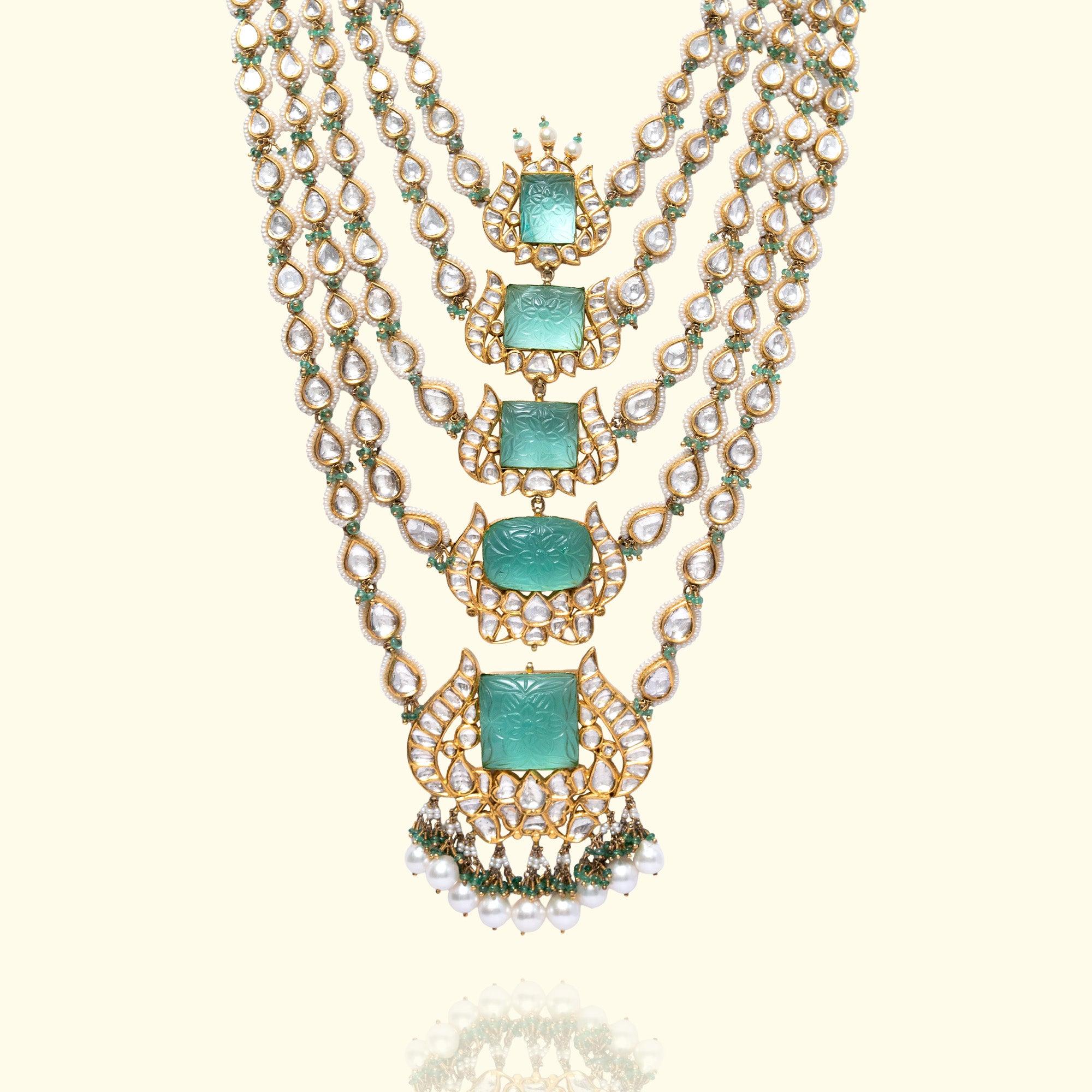 A magnificent multi-strand Satlada-style necklace featuring graduated rows of teardrop polki diamonds and emerald beads, anchored by five central carved emerald plaques in ornate floral gold settings with pearl and emerald fringe.