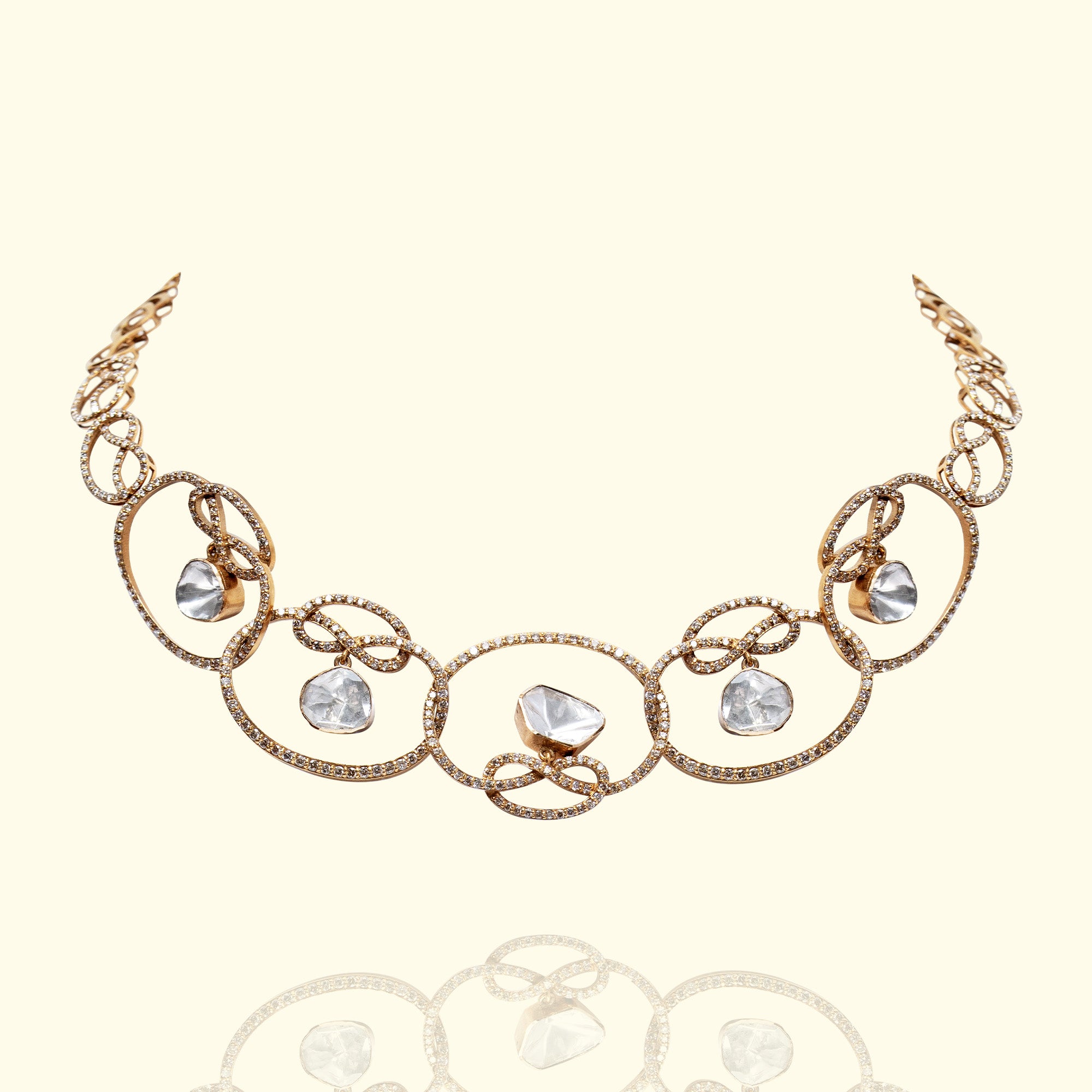A contemporary gold polki necklace featuring a sequence of interlocking infinity-style loops encrusted with shimmering pavé diamonds, each framing a central, bezel-set triangular uncut diamond.