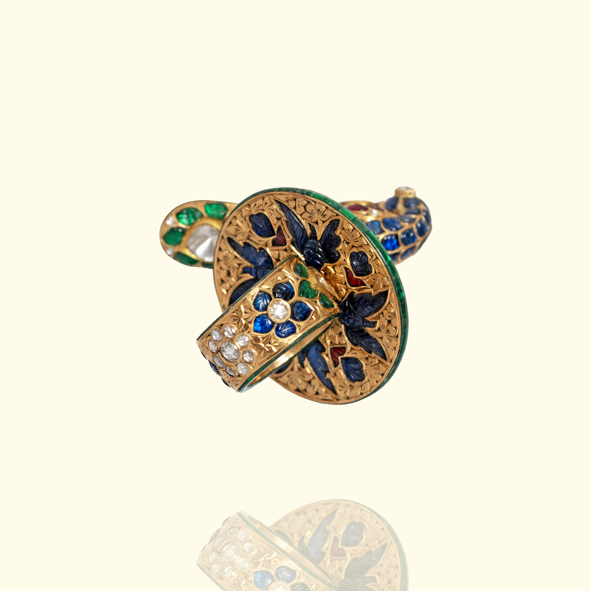 A detailed view of the intricate gold-work and floral blue enamel patterns on the underside of a statement cocktail ring.