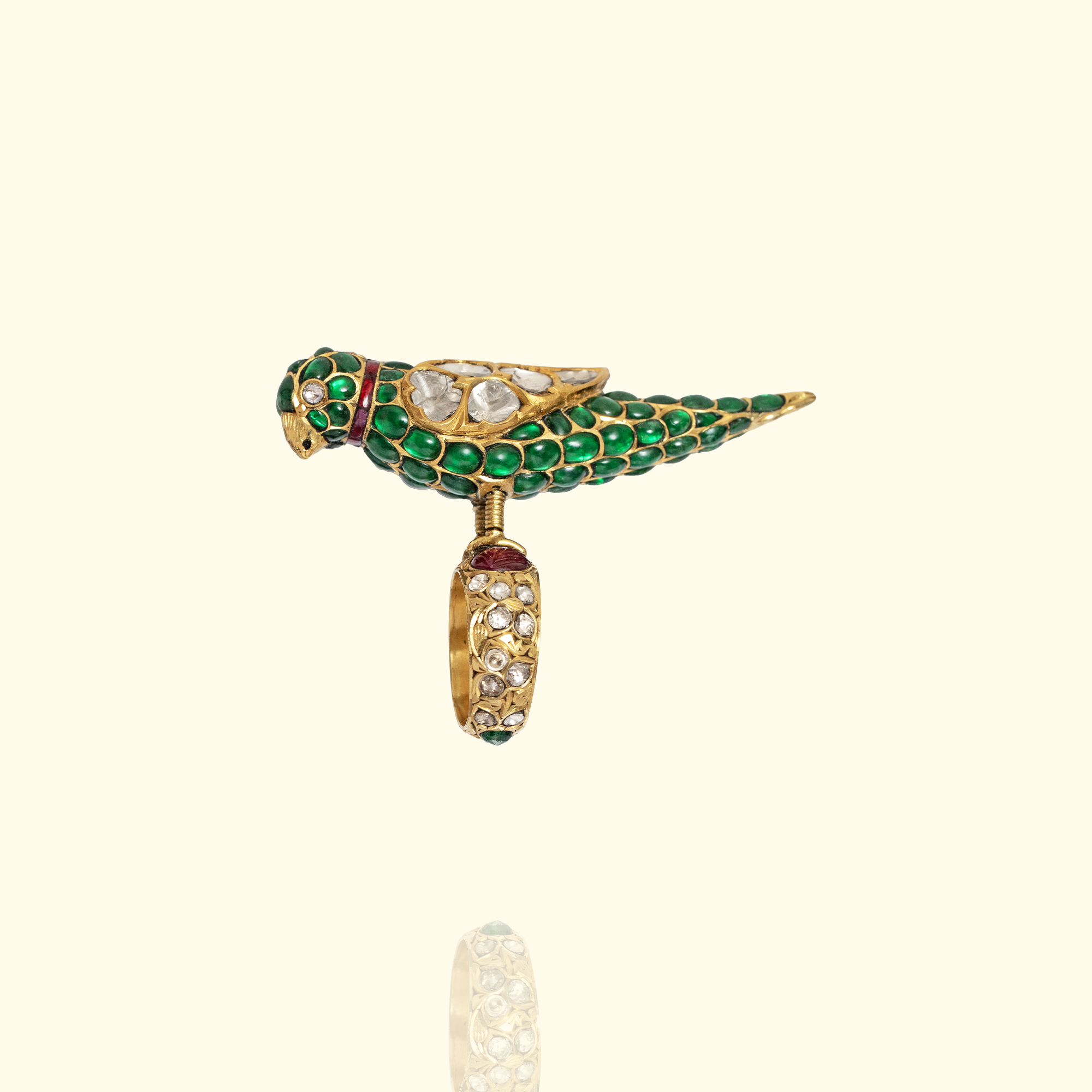 A whimsical 3D bird statement ring featuring a body encrusted with vibrant green emeralds and polki diamond wings.