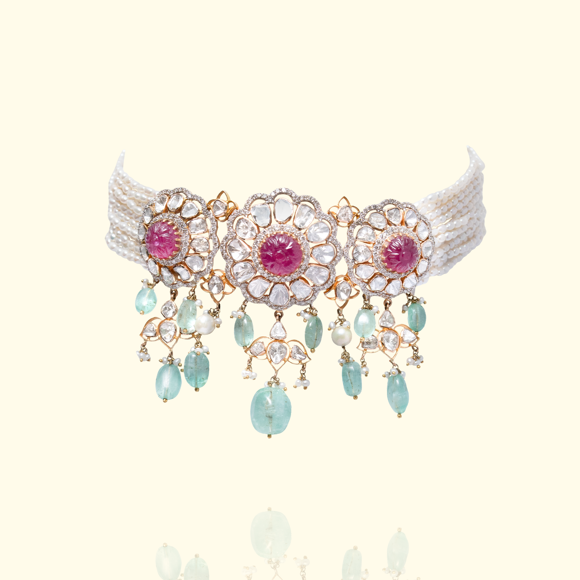 A multi-strand seed pearl choker featuring three large, circular polki diamond medallions with carved ruby cabochon centers, finished with a delicate fringe of mint-green emerald drops and seed pearls.