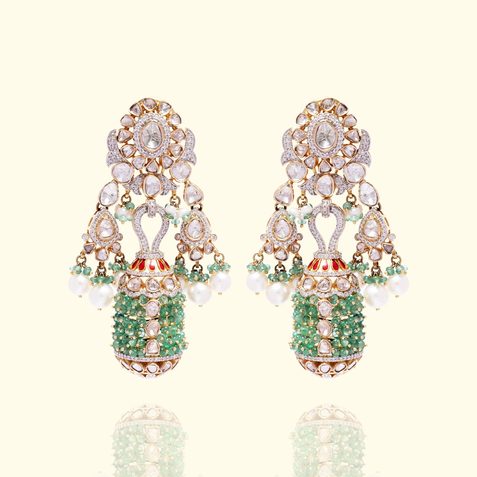 A pair of ornate gold polki earrings featuring a floral uncut diamond stud that supports a unique cylindrical tassel encrusted with vibrant emerald beads, accented by small japanese freshwater pearl drops and delicate brilliant cut diamond-set scrollwork.
