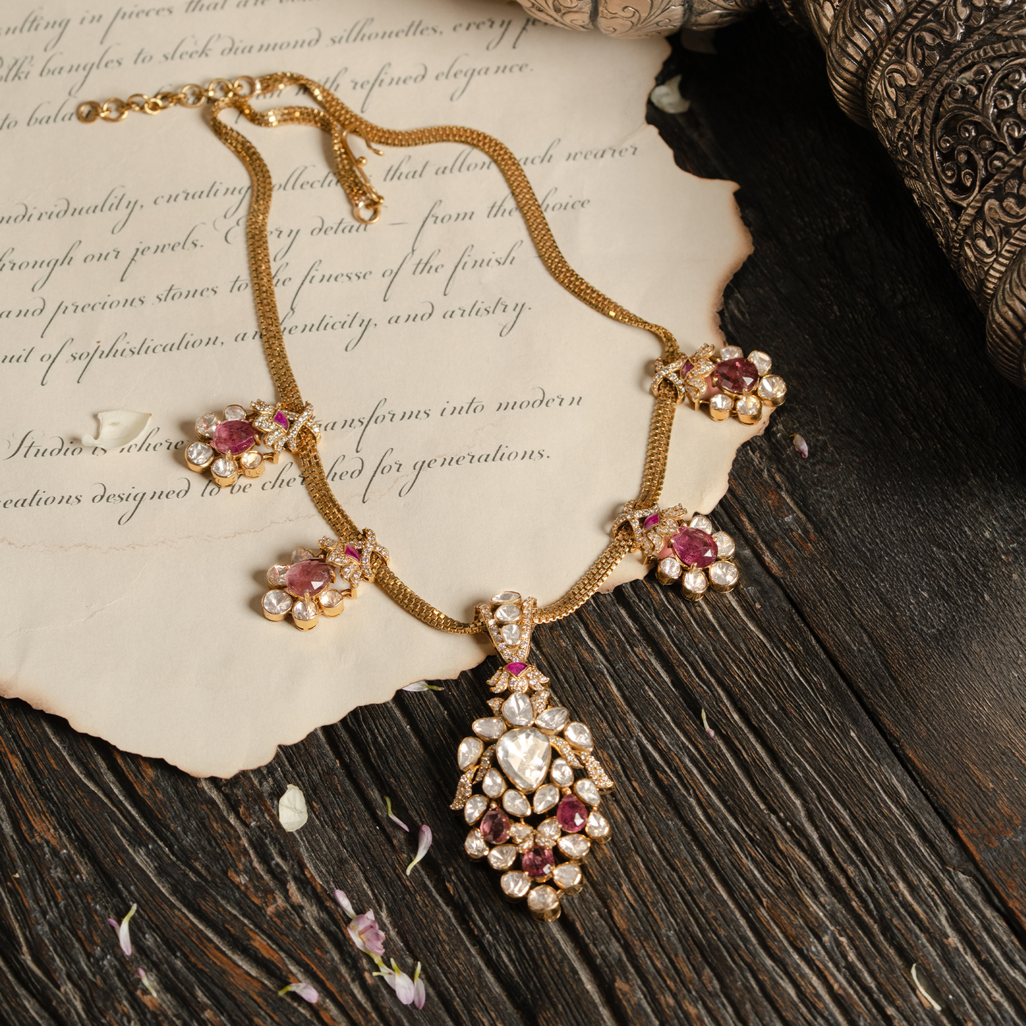 A delicate gold chain necklace featuring four pink tourmaline and polki diamond floral charms and a large, coordinating pear-shaped drop polki pendant.