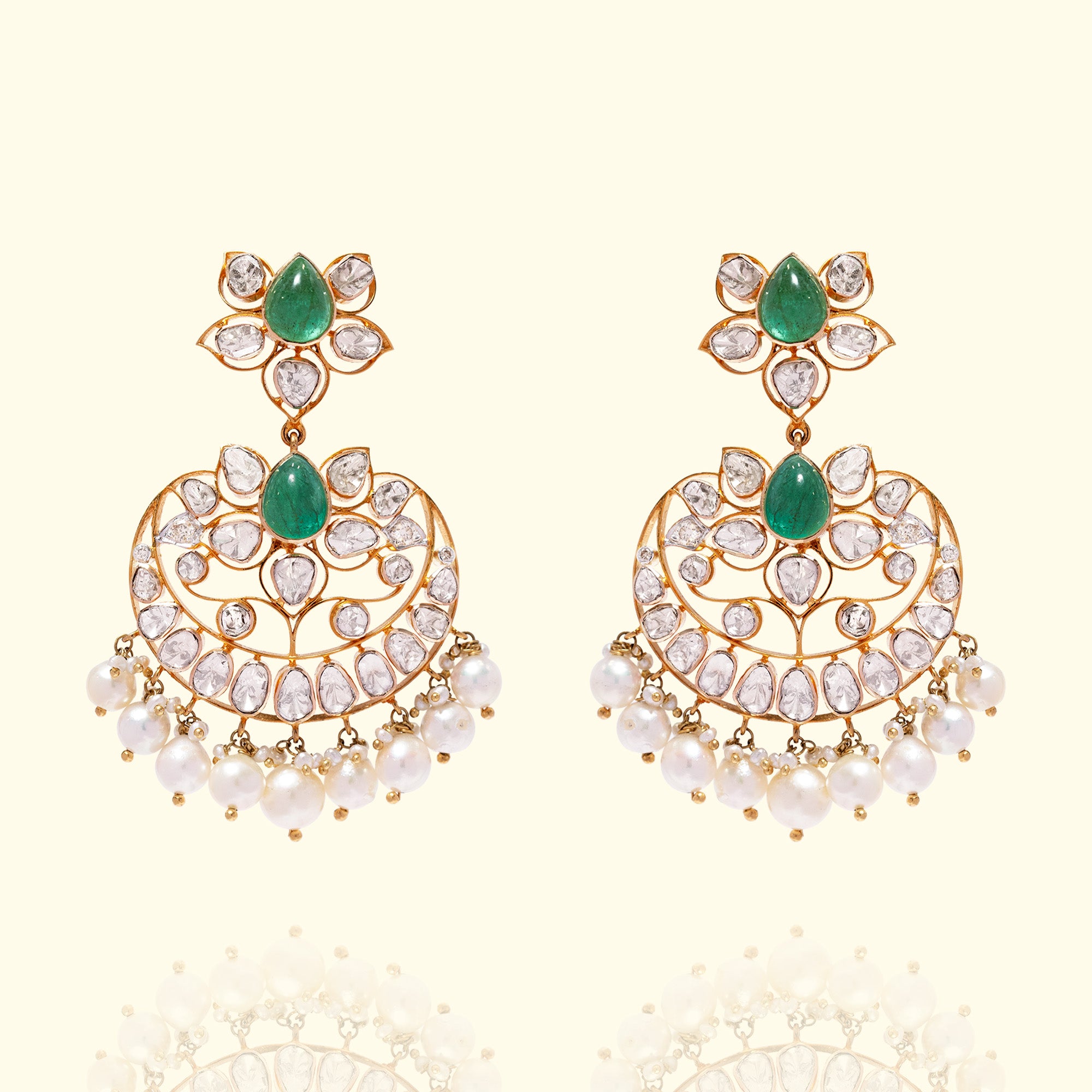 Intricate gold chandelier earrings with emerald gemstones and Polki diamonds, traditional Indian jewelry style