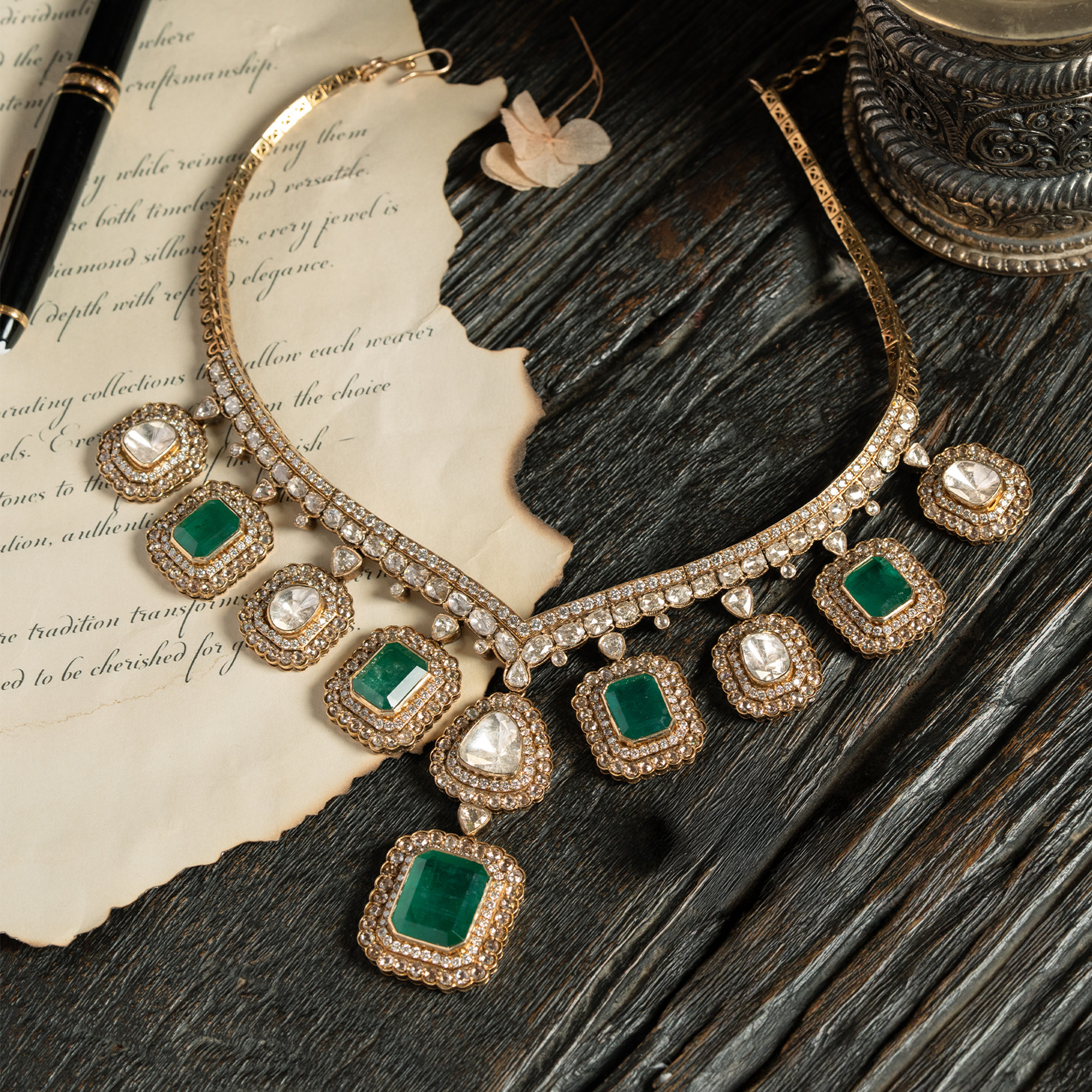 A majestic gold collar necklace featuring alternating square-cut emeralds and polki diamonds in pavé halos, finished with a large, rectangular emerald-cut emerald pendant in india