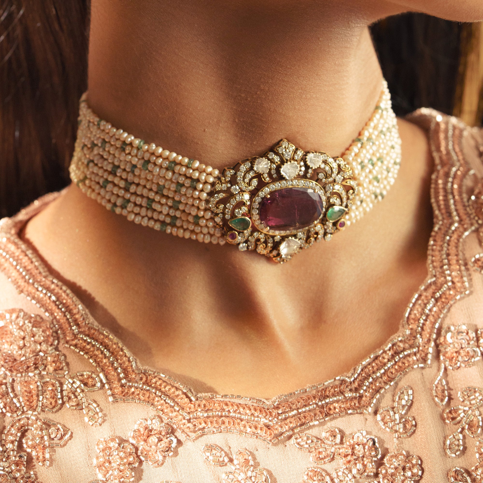 Close-up of a person wearing an ornate necklace with gemstones and beads in india