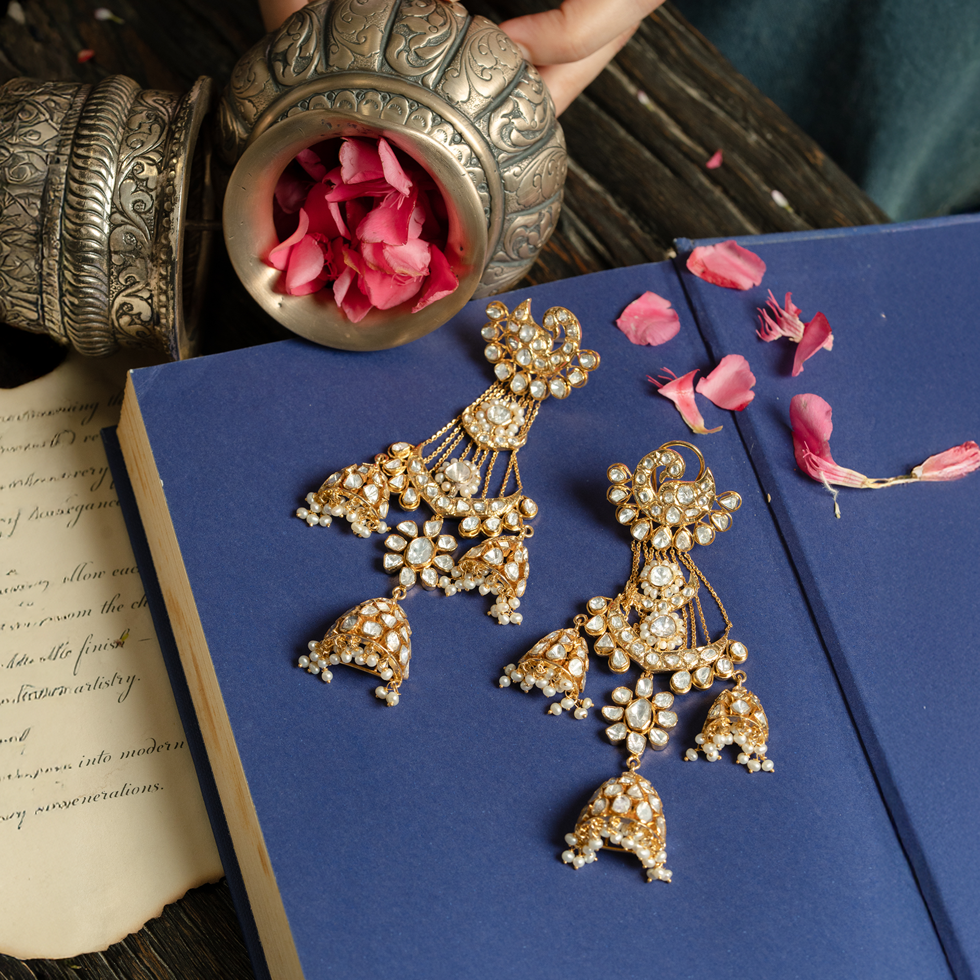 pair of elaborate gold chandelier earrings featuring peacock motifs, polki diamond floral elements, and cascading pearl-fringed jhumkas.