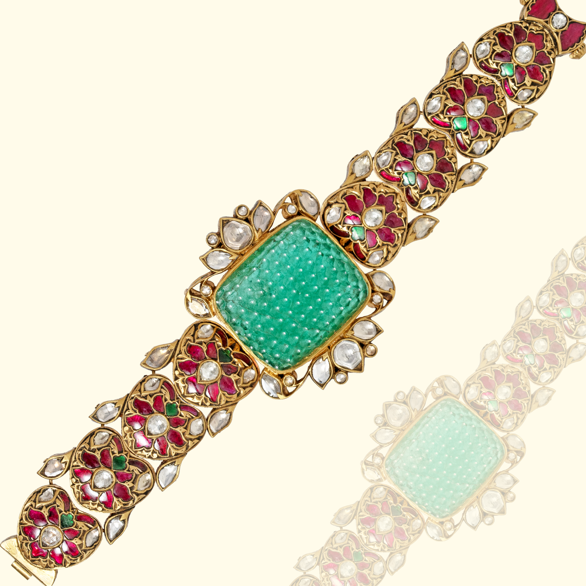 An intricate gold link bracelet featuring a large, central square-cut carved emerald flanked by polki diamond and ruby floral-motif links.