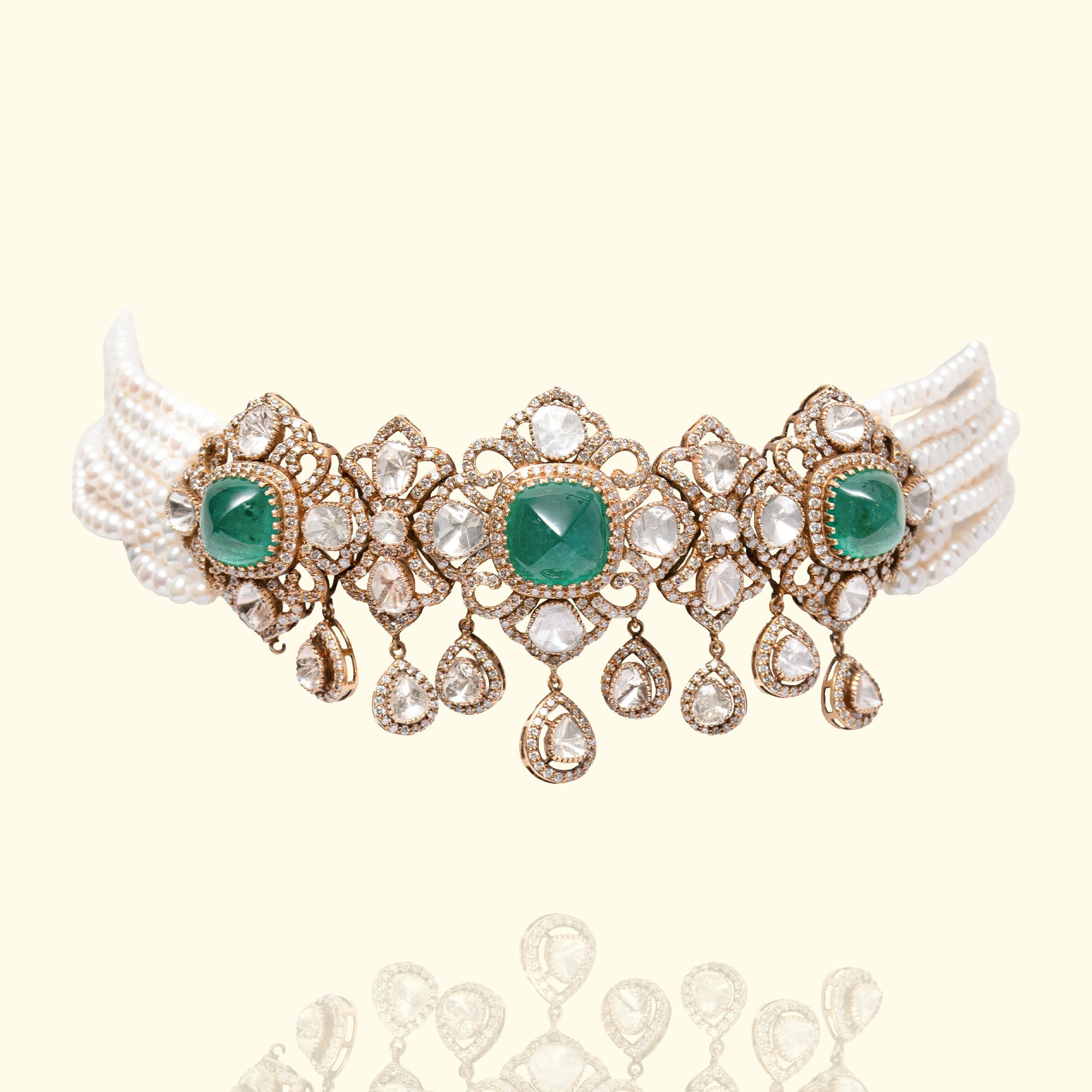 Luxury multi-strand pearl choker featuring three large emerald cabochon centers set in intricate gold and Polki diamond frames with dangling pear-shaped uncut diamond charms.
