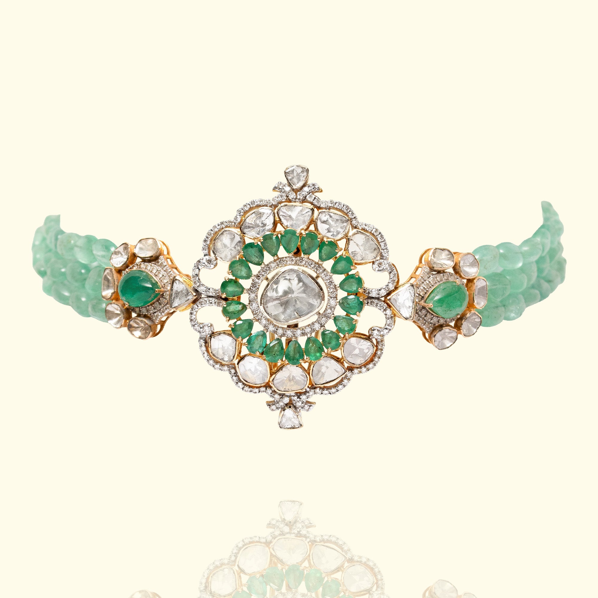 Ornate gold emerald and Polki collar necklace featuring featuring three strands of vibrant emerald beads connected to a large, alternating rectangular emerald and pear-shaped polki diamond stations with pavé-set round diamond borders.