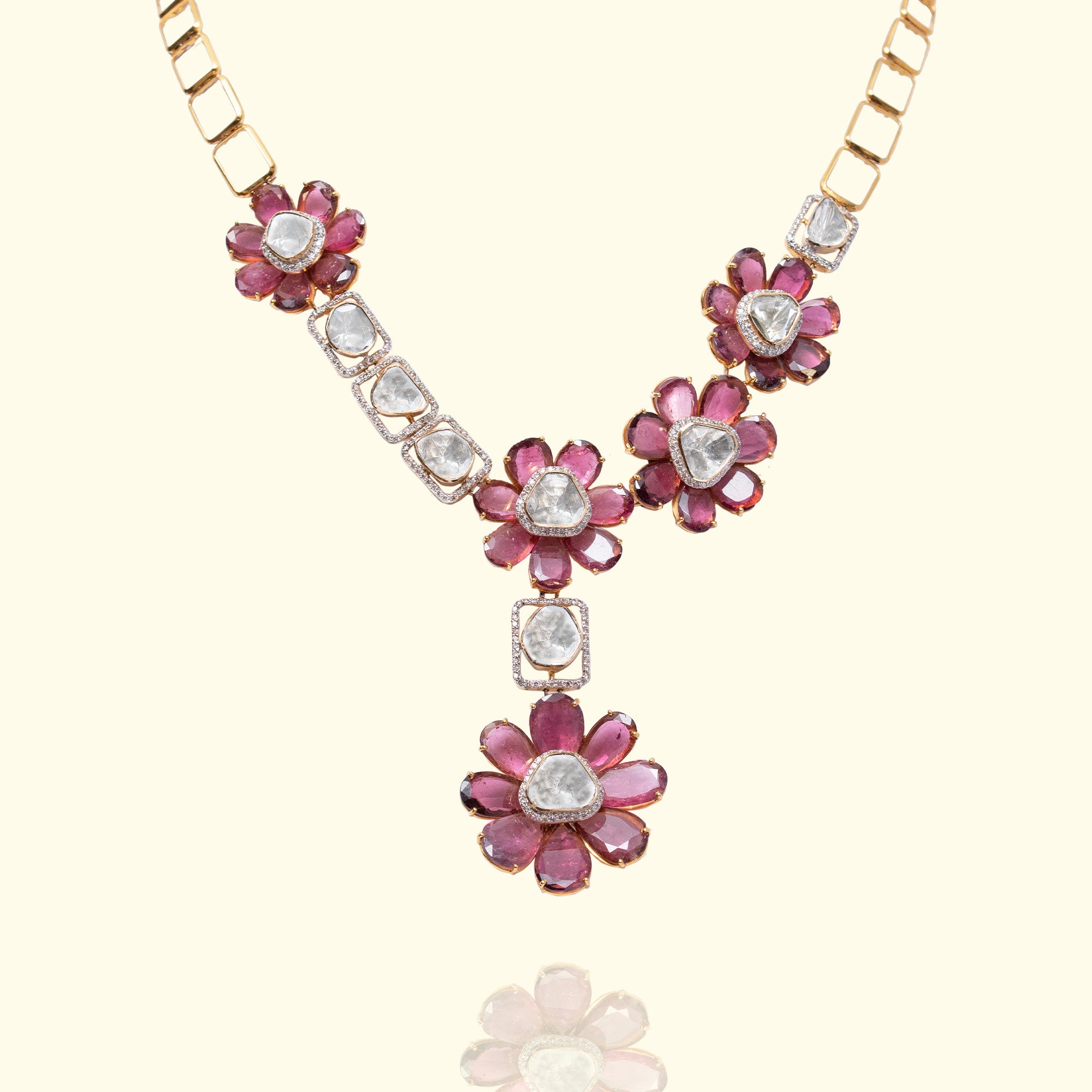 A contemporary gold polki necklace featuring an asymmetrical arrangement of floral motifs with vibrant tourmaline petal and central polki diamonds, interspersed with geometric rectangular links encrusted with pavé diamonds and additional uncut diamonds.