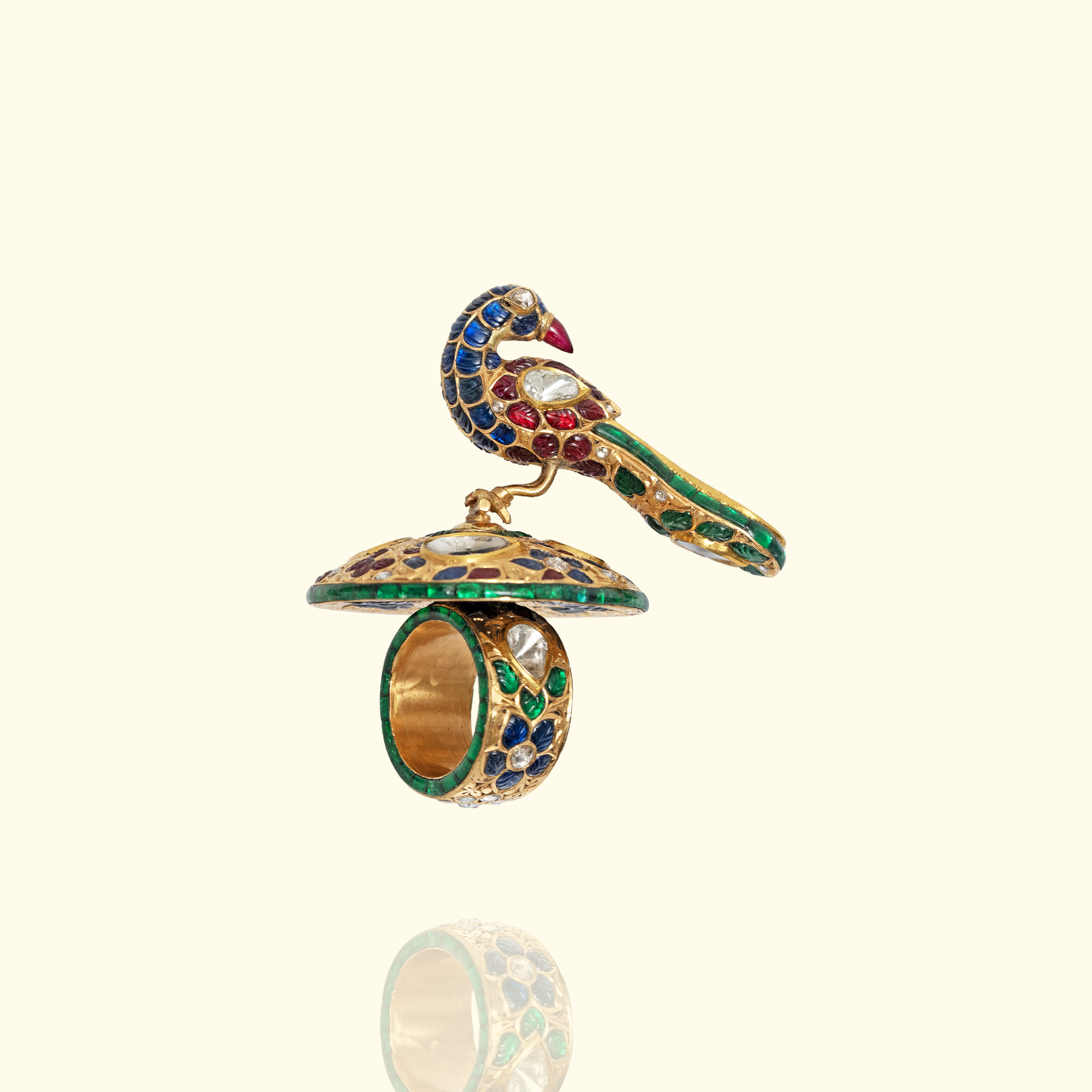 High-jewelry gold peacock statement ring featuring intricate blue and green gemstone inlay, Polki diamond accents, and a wide band with floral engravings.