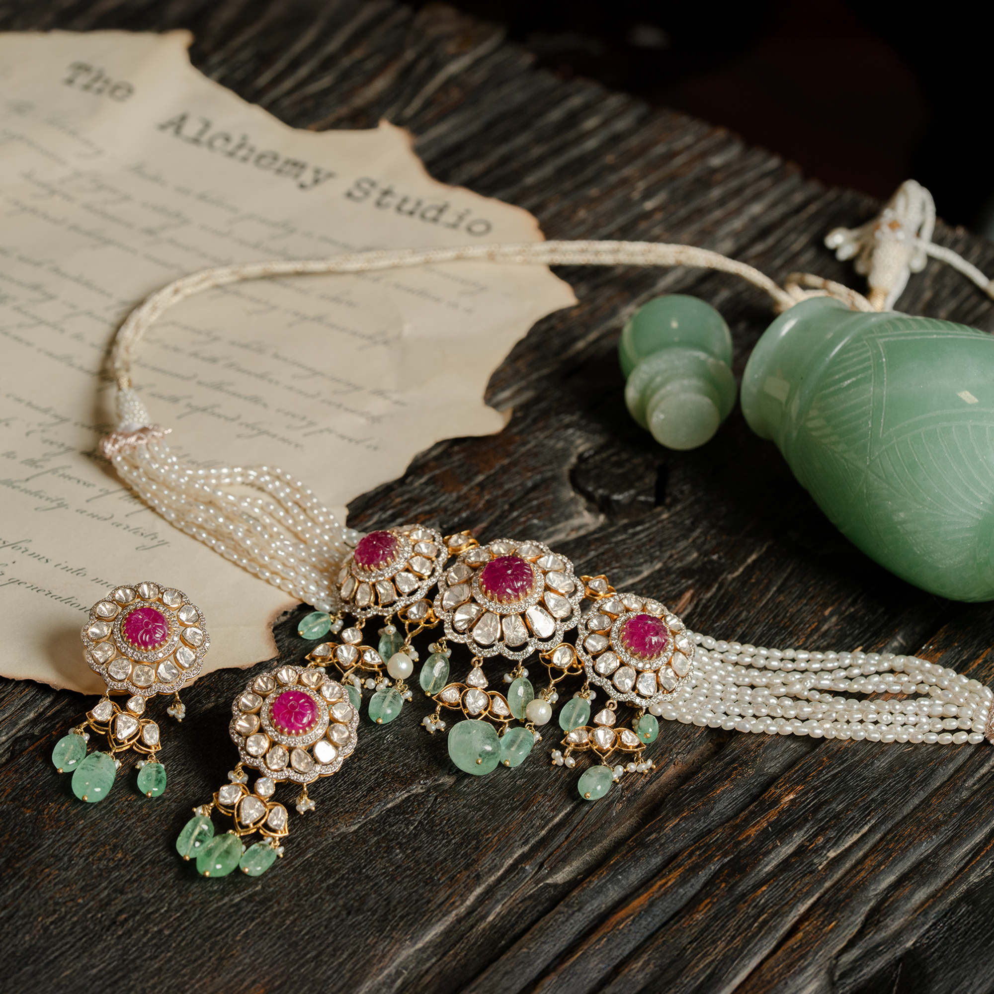 A coordinated polki jewelry set featuring a multi-strand seed pearl choker with three large, circular uncut diamond medallions centered by carved ruby cabochons, paired with matching floral drop earrings that feature ruby centers and mint-green emerald bead fringes.