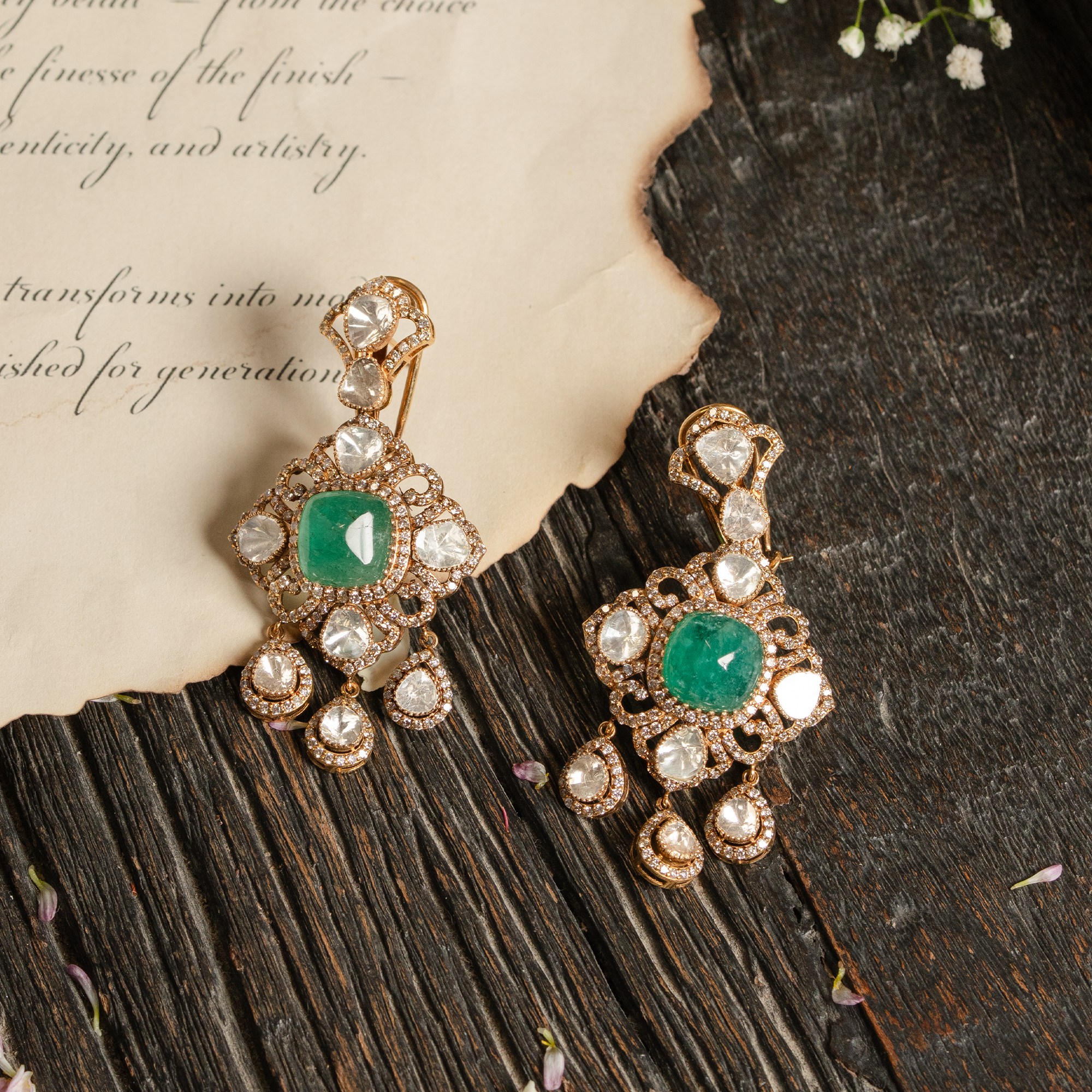 A model wearing an oversized, regal statement ring featuring a central polki diamond surrounded by a sunburst of vibrant emeralds and a double halo of sparkling diamonds.