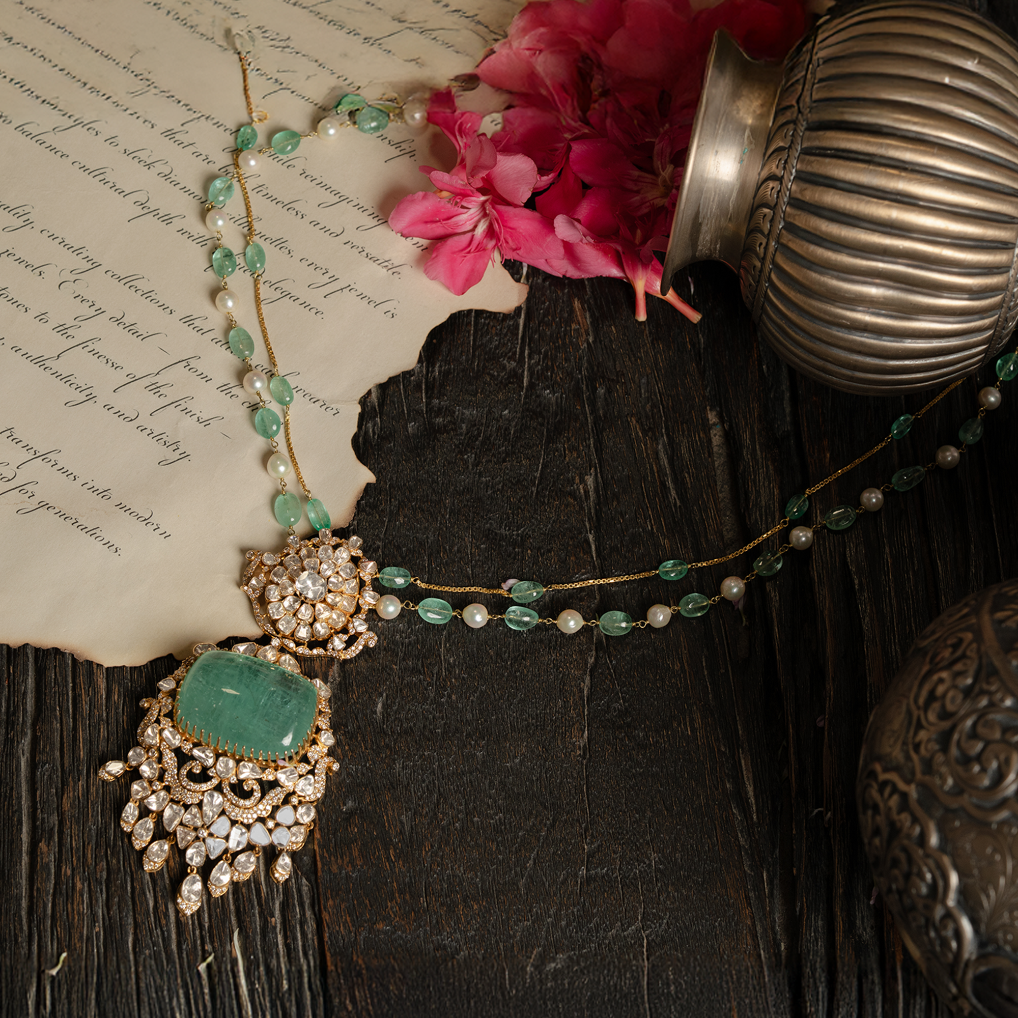 A regal gold necklace featuring a delicate chain of emerald beads and pearls, leadings to a massive, rectangular emerald cabochon pendant framed by ornate polki diamond scrollwork and cascading pear-shaped diamond drops.