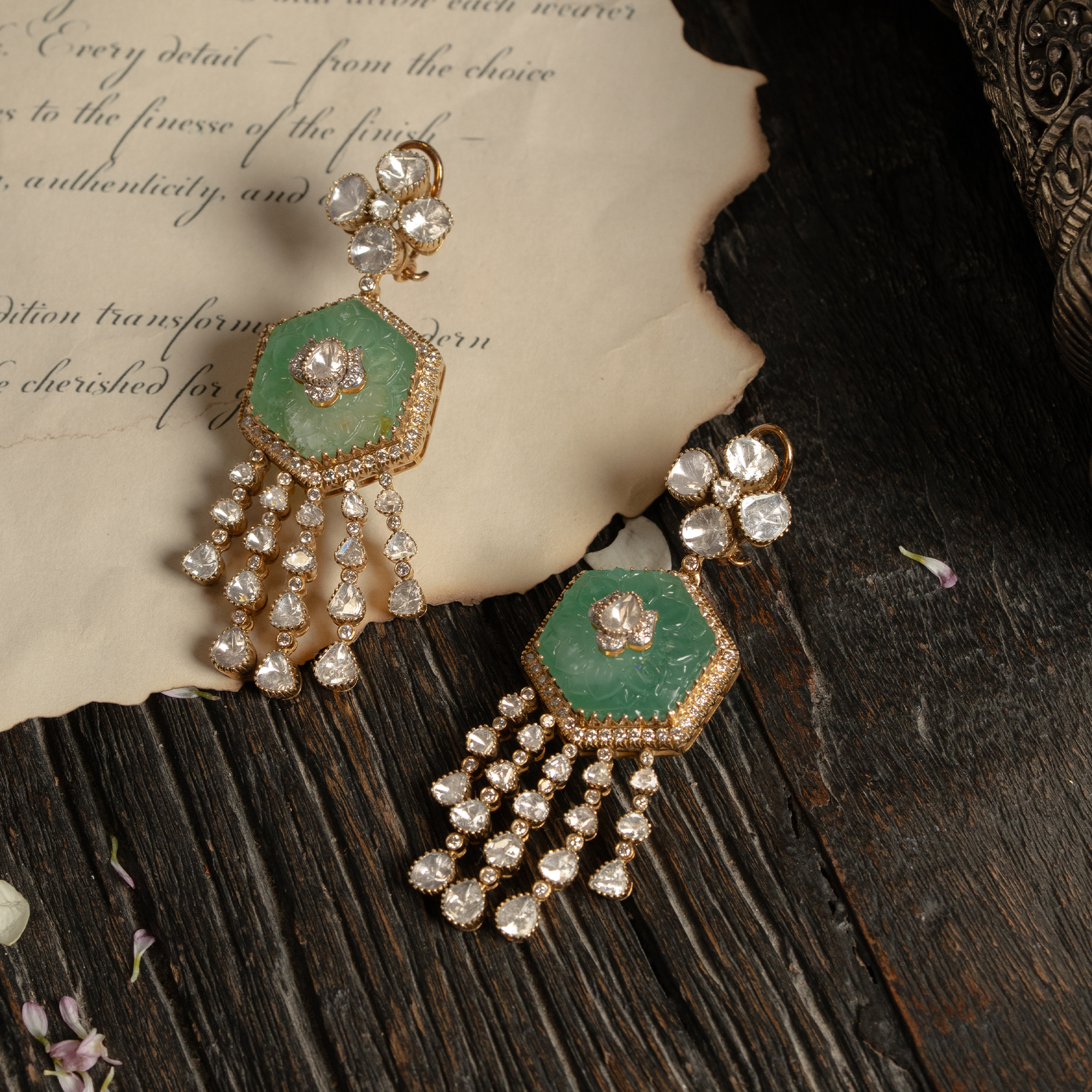 A striking hexagonal carved emerald earring featuring a floral polki diamond stud and multiple cascading uncut diamond-encrusted tassels.