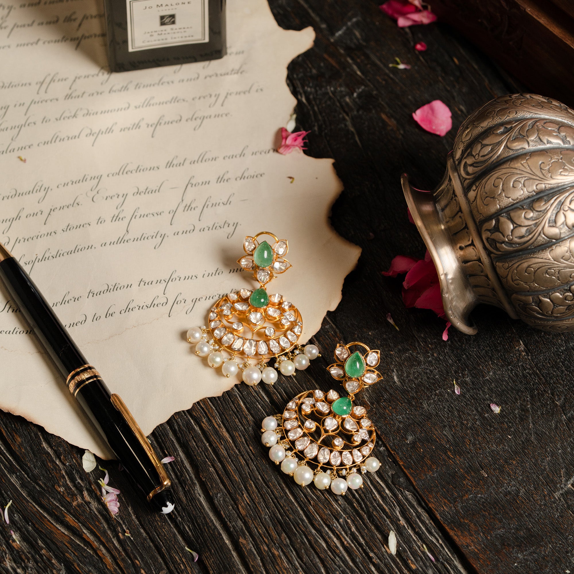 Intricate gold chandelier earrings with emerald gemstones and Polki diamonds, traditional Indian jewelry style