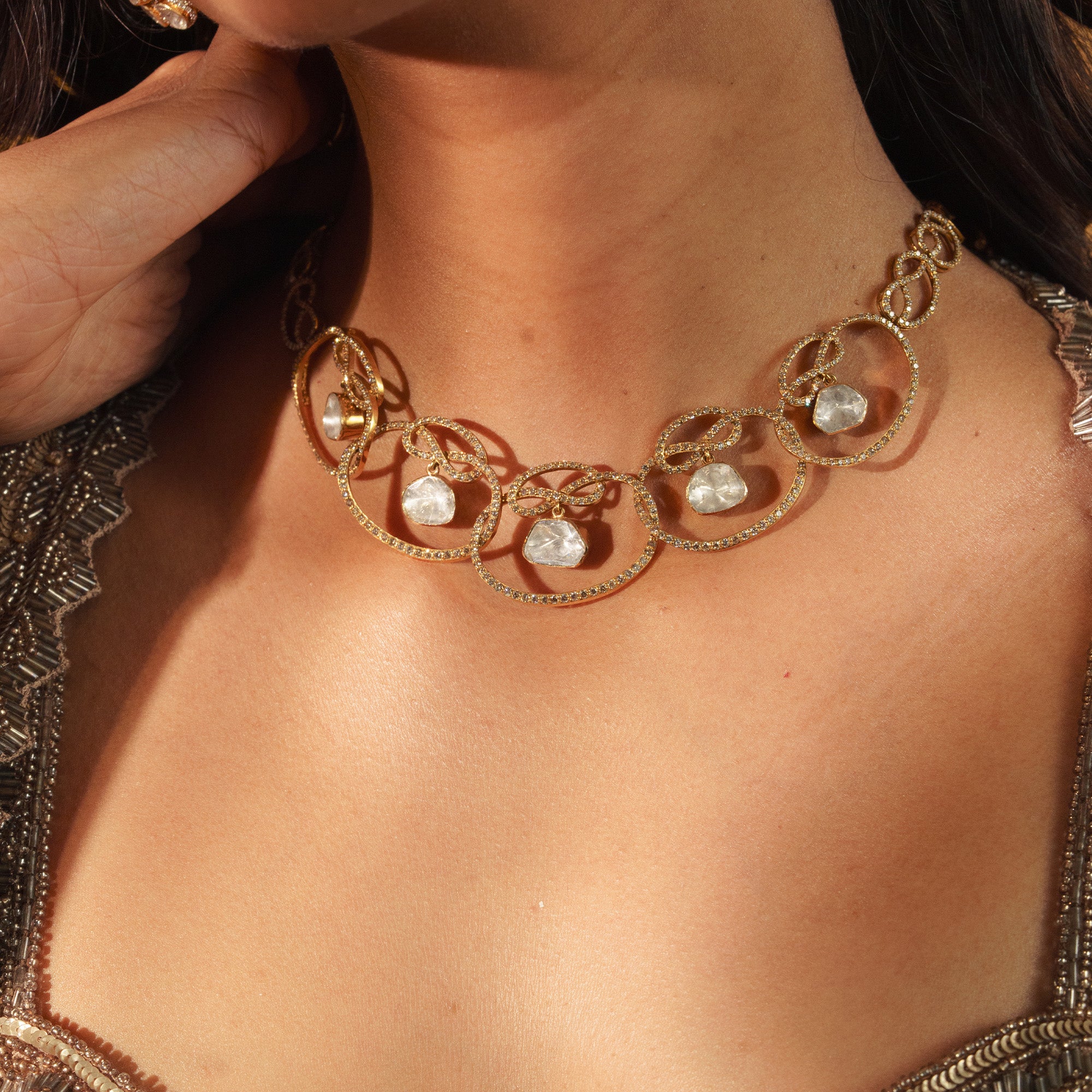Model wearing a contemporary gold Polki necklace featuring interlocking diamond-pave hoops with dangling organic-shaped uncut diamonds.