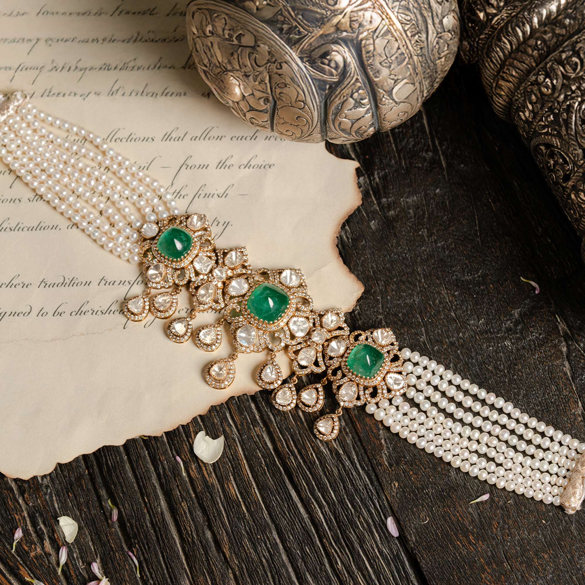 Luxury multi-strand pearl choker featuring three large emerald cabochon centers set in intricate gold and Polki diamond frames with dangling pear-shaped uncut diamond charms.