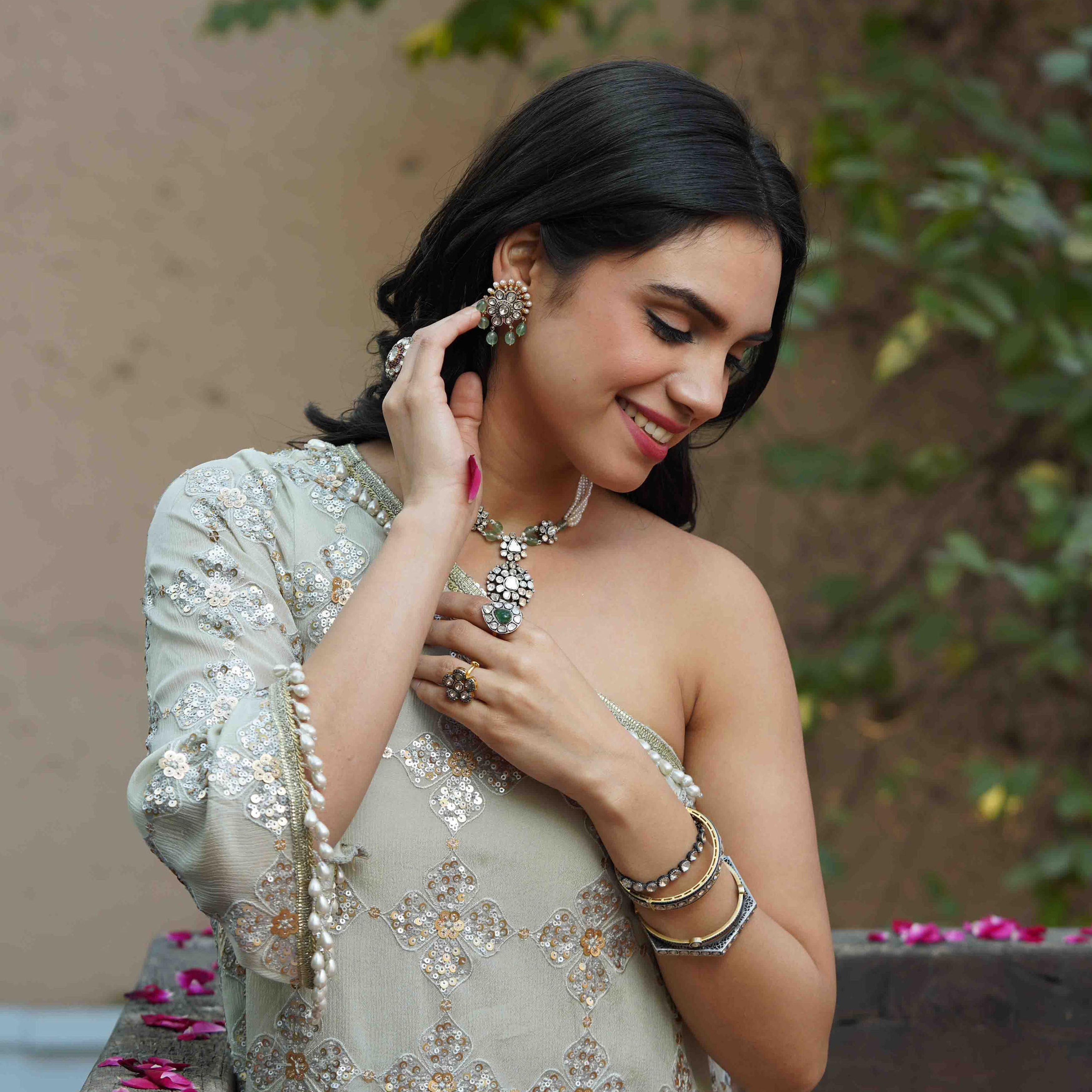 A diverse collection of luxury Polki diamond and emerald jewelry, featuring high-fashion bridal looks with layered necklaces and statement rings, alongside detailed product shots of handcrafted necklaces and floral-inspired rings set in gold.